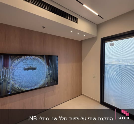 חדר עם מסך טלוויזיה וקיר עץ, חלון ודלת זכוכית.